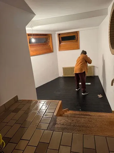 Derselbe Kellerraum nach der Sanierung: Wände glatt verputzt und weiß gestrichen, neuer dunkler Laminatboden verlegt, Raum besenrein übergeben.
