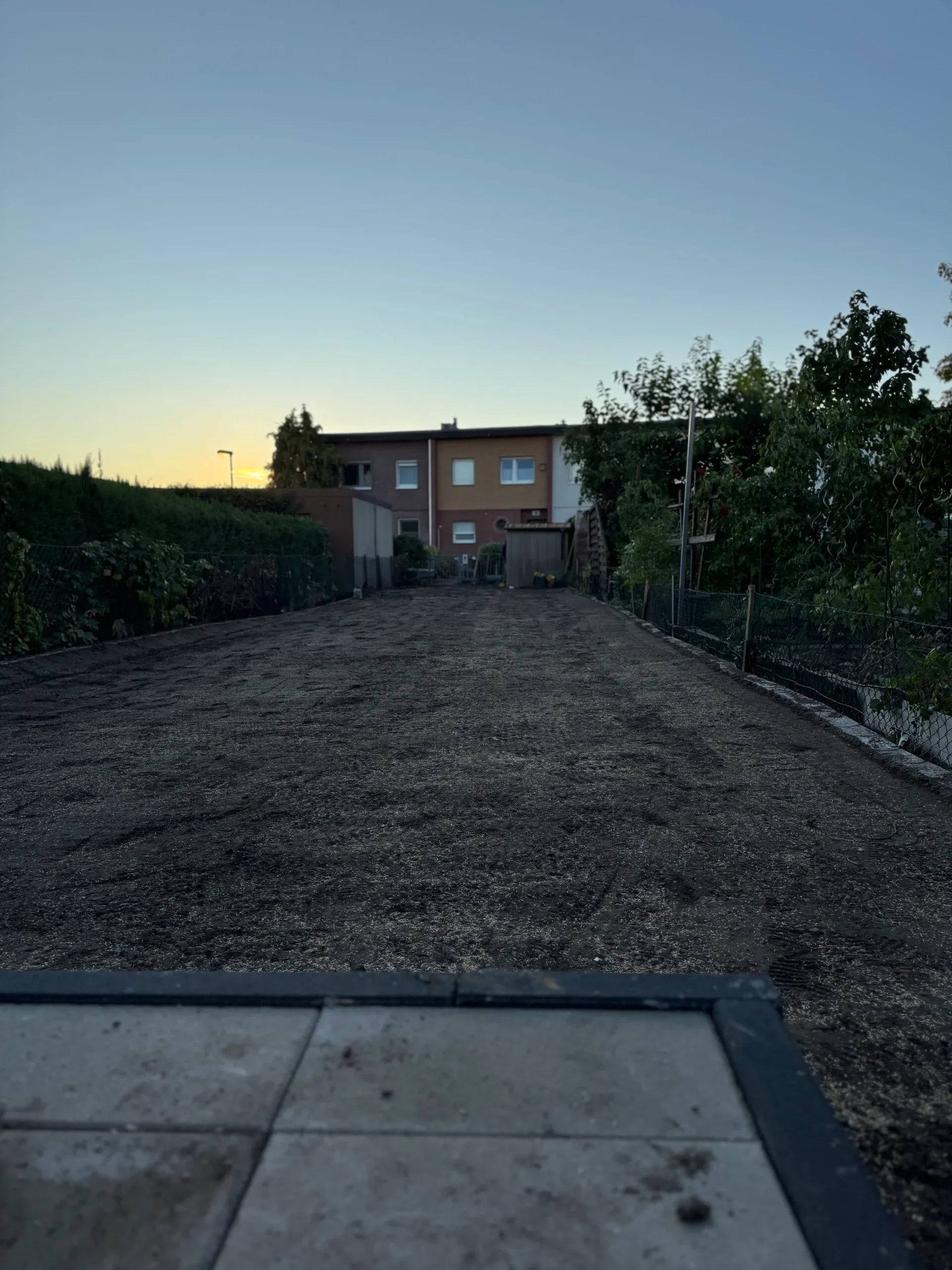 Dieselbe Gartenfläche nach der Rodung: Wildwuchs entfernt, neue Erde aufgebracht und eben abgezogen, das Feinplanum ist frisch eingesät.